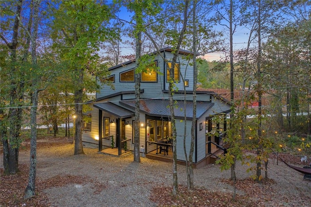 back house at dusk featuring a porch