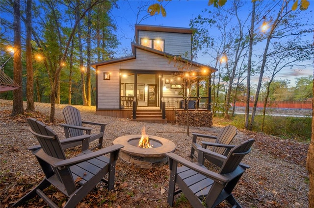 back house at dusk with a porch and a fire pit