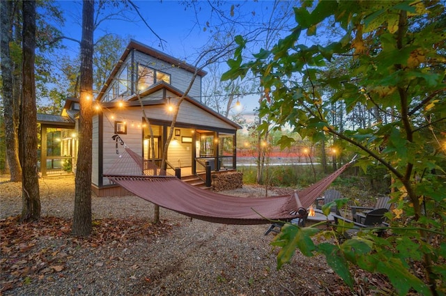 back house at dusk featuring a porch