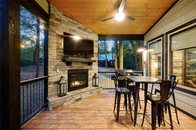 wooden deck featuring an outdoor stone fireplace and ceiling fan