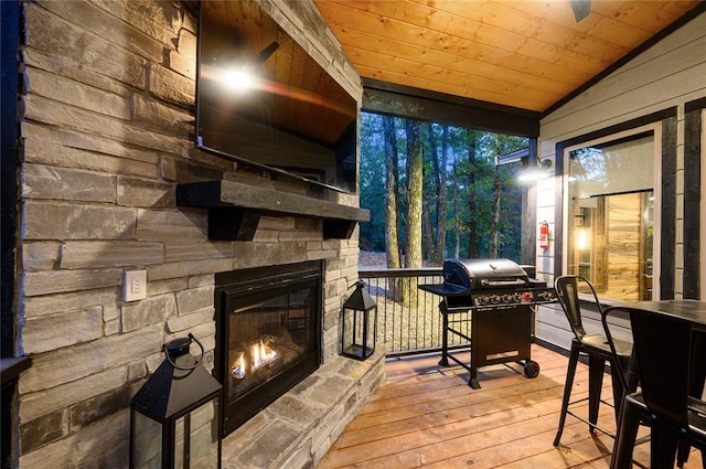 wooden deck featuring a grill and an outdoor stone fireplace