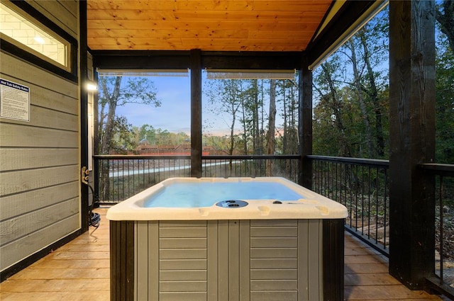 unfurnished sunroom with a water view, wooden ceiling, and a hot tub