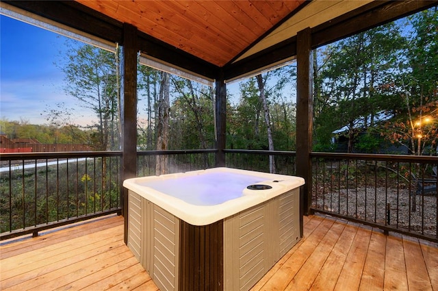 deck at dusk featuring a hot tub