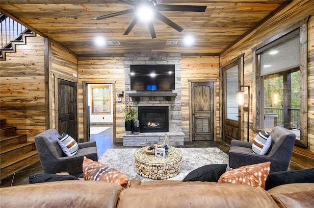 living room featuring wood walls, wooden ceiling, ceiling fan, a fireplace, and wood-type flooring