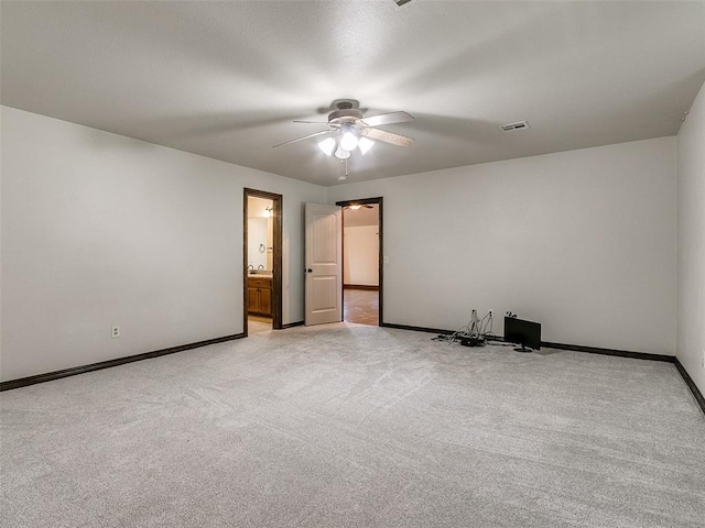 unfurnished bedroom featuring ceiling fan, light colored carpet, and ensuite bath