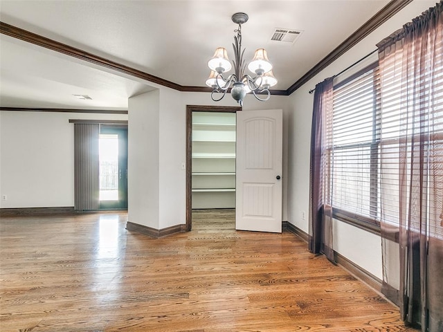 unfurnished dining area with hardwood / wood-style flooring, ornamental molding, and a chandelier