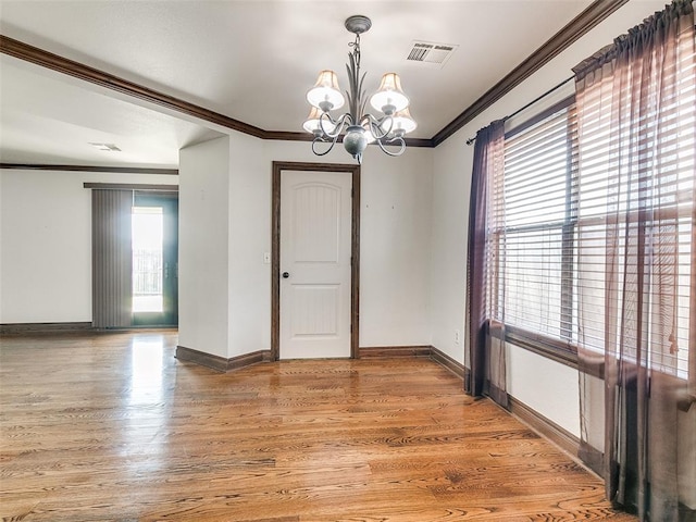 empty room featuring crown molding, wood-type flooring, and an inviting chandelier