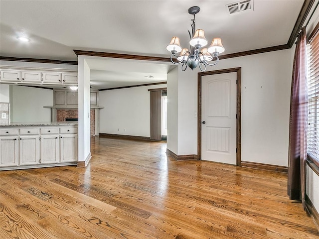 unfurnished dining area featuring a notable chandelier, light wood-type flooring, and ornamental molding