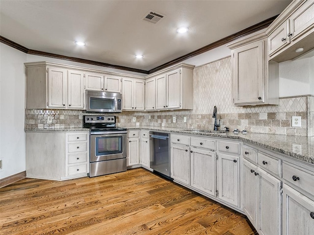 kitchen featuring sink, backsplash, crown molding, appliances with stainless steel finishes, and light wood-type flooring