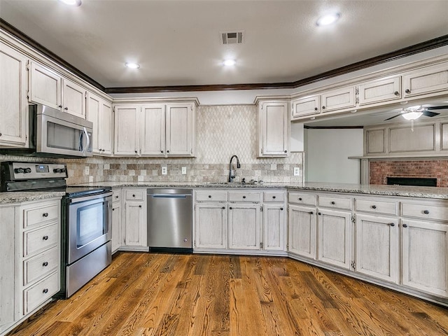 kitchen featuring appliances with stainless steel finishes, sink, white cabinetry, and wood-type flooring