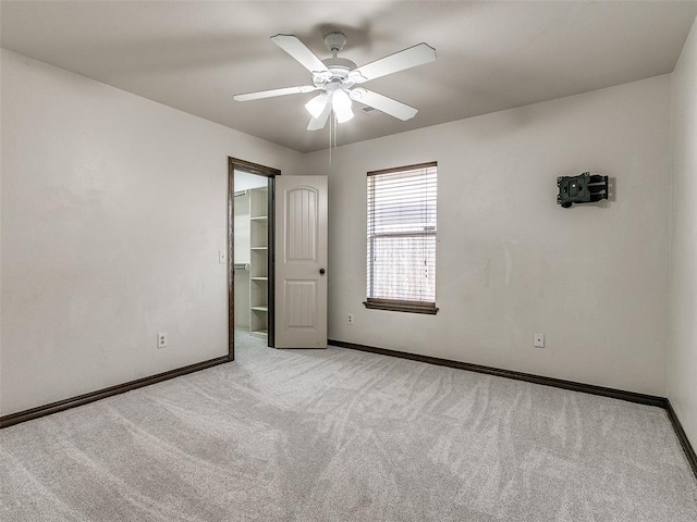 unfurnished bedroom with ceiling fan, light colored carpet, a spacious closet, and a closet