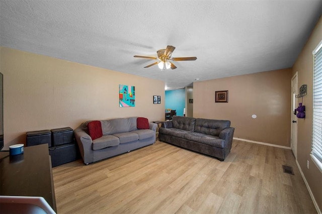 living room with a wealth of natural light, ceiling fan, light hardwood / wood-style floors, and a textured ceiling