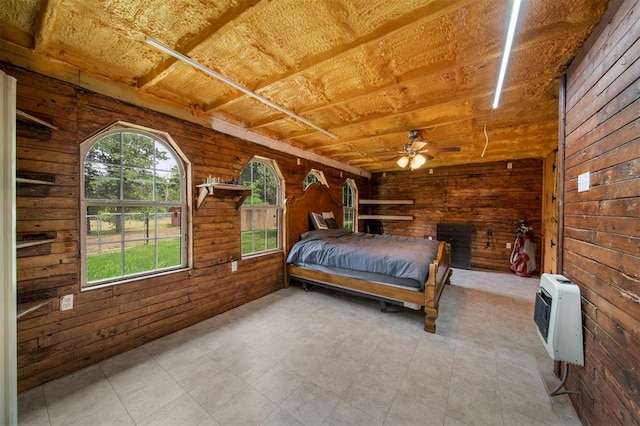 unfurnished bedroom with ceiling fan, wood walls, and heating unit