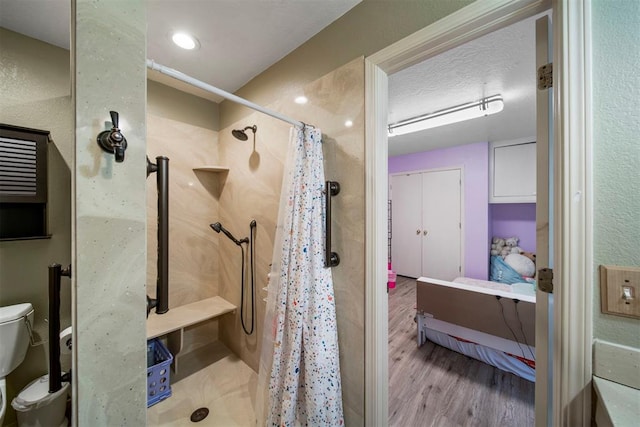 bathroom featuring a shower with shower curtain, toilet, wood-type flooring, and a textured ceiling