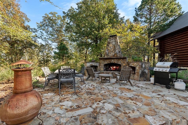 view of patio featuring an outdoor stone fireplace and grilling area