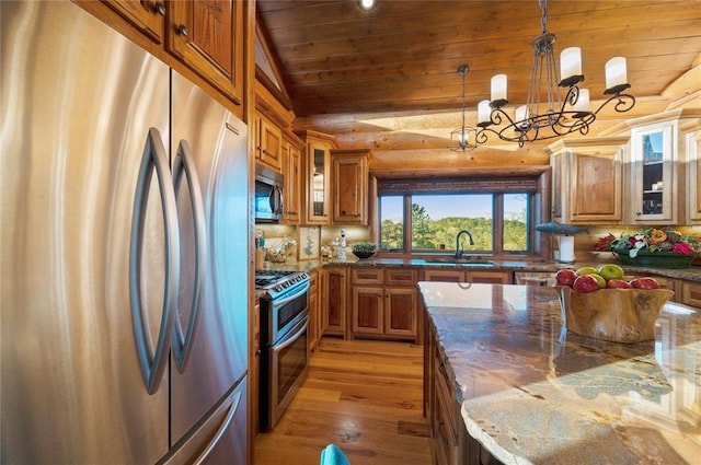 kitchen featuring wood ceiling, stainless steel appliances, sink, decorative light fixtures, and dark stone countertops