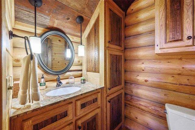 bathroom with wood walls, vanity, and toilet