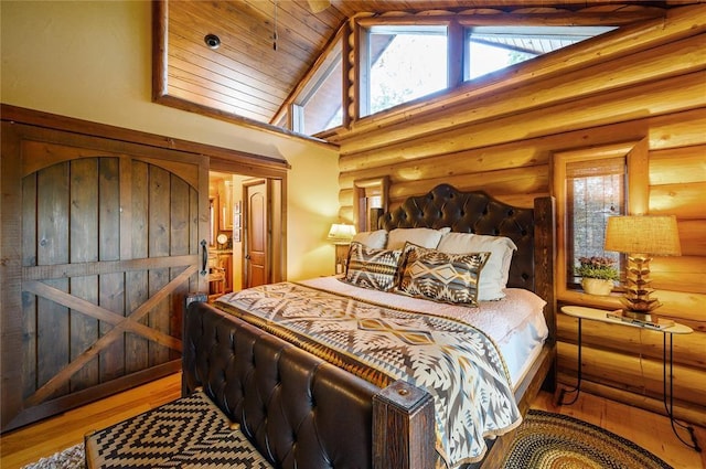 bedroom with hardwood / wood-style flooring, rustic walls, and multiple windows