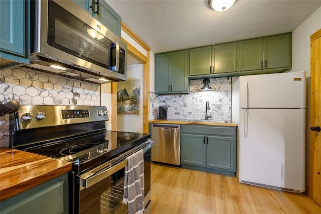 kitchen with wooden counters, sink, decorative backsplash, light hardwood / wood-style floors, and stainless steel appliances