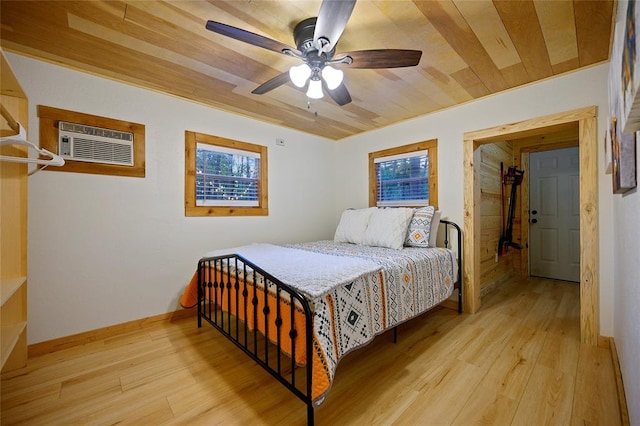 bedroom featuring ceiling fan, light wood-type flooring, a wall unit AC, and wooden ceiling