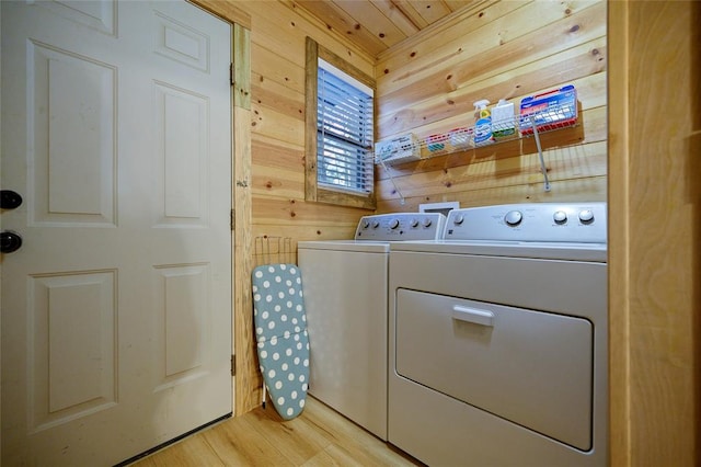 washroom featuring light hardwood / wood-style floors, separate washer and dryer, and wooden walls