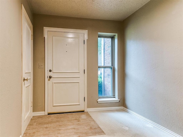 entryway with light hardwood / wood-style floors and a textured ceiling