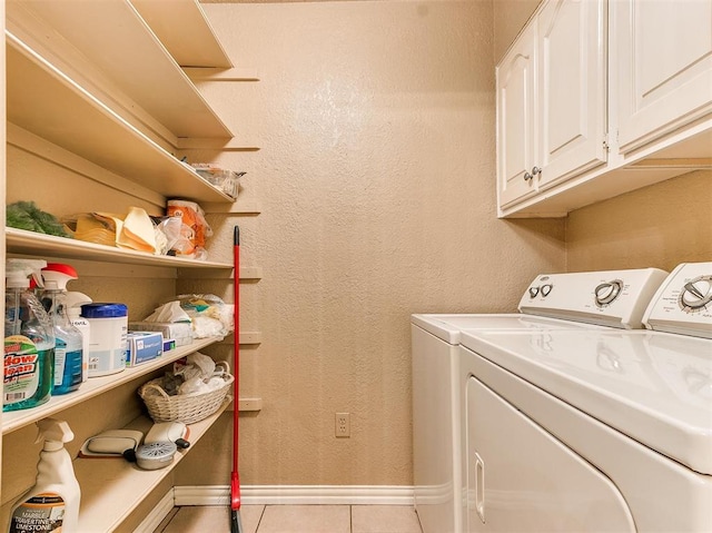 laundry area featuring washing machine and dryer, light tile patterned floors, and cabinets