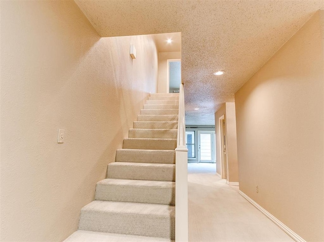 staircase featuring carpet and a textured ceiling