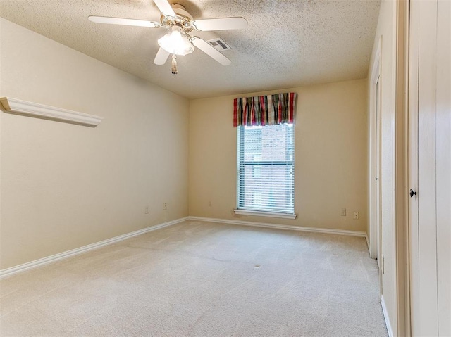 spare room with ceiling fan, a textured ceiling, and light carpet