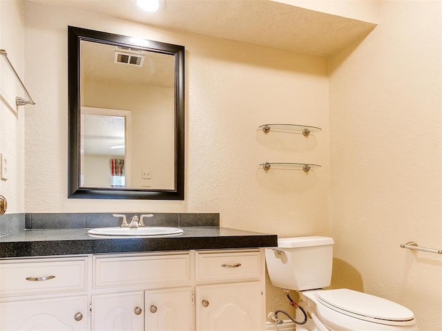 bathroom featuring a textured ceiling, vanity, and toilet