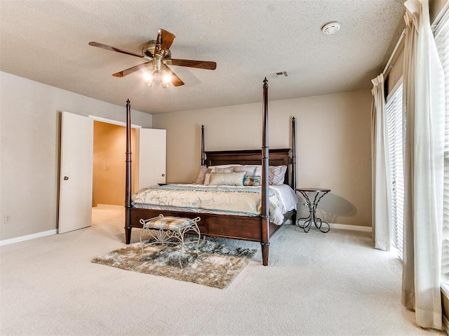 bedroom with ceiling fan, light colored carpet, and a textured ceiling