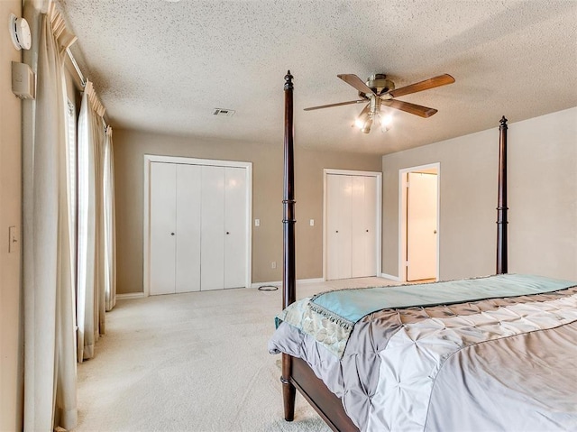 bedroom with ceiling fan, light carpet, and a textured ceiling