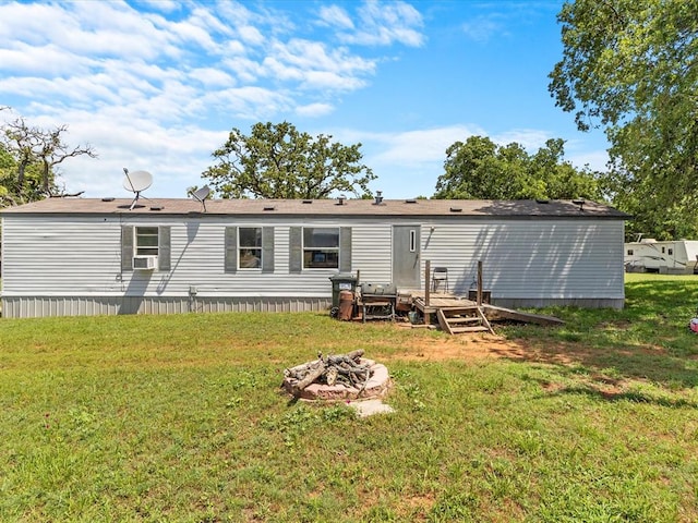 back of property with a lawn and an outdoor fire pit