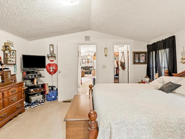 carpeted bedroom with a textured ceiling, a walk in closet, vaulted ceiling, and a closet