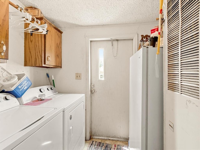 laundry area with cabinets, a textured ceiling, and washing machine and clothes dryer