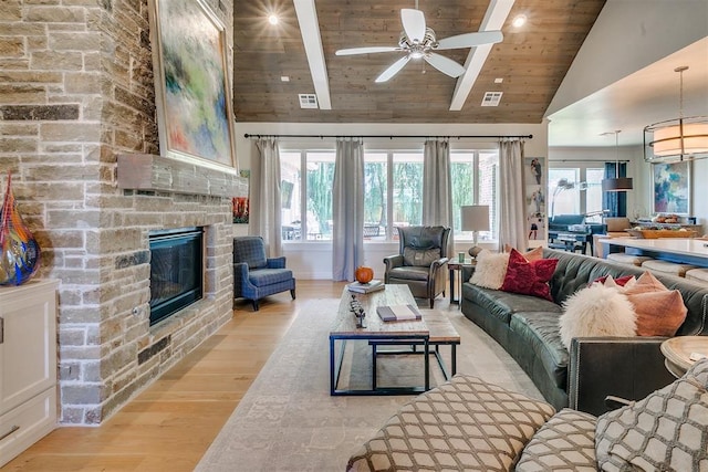 living room with wooden ceiling, high vaulted ceiling, a stone fireplace, ceiling fan, and light hardwood / wood-style floors