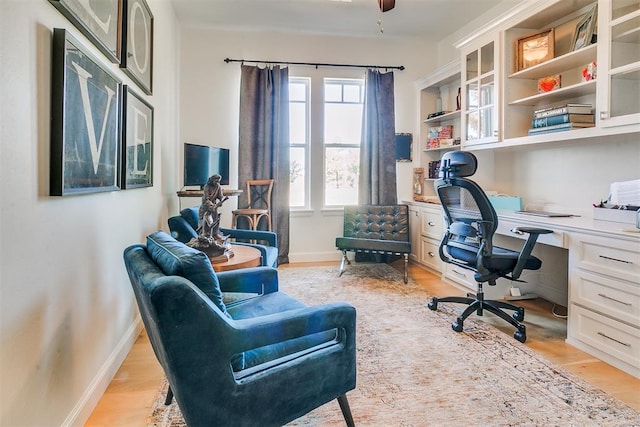 office space with built in desk and light hardwood / wood-style floors