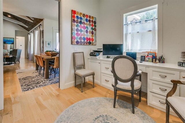 home office featuring light hardwood / wood-style floors, built in desk, and vaulted ceiling