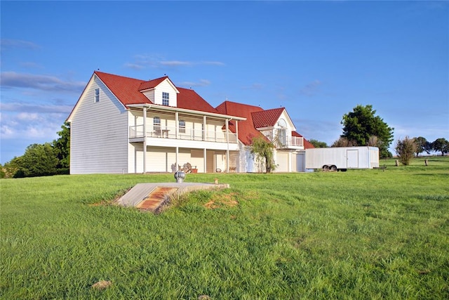 rear view of house with a lawn and a balcony