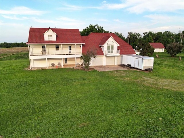 rear view of property featuring a lawn, a balcony, and a garage