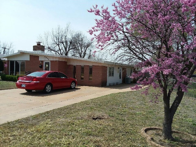 ranch-style home featuring central AC unit and a front yard