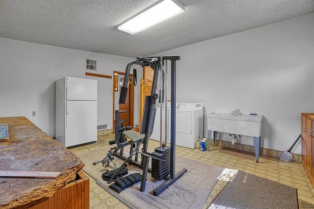 exercise room with washer / dryer, a textured ceiling, and sink