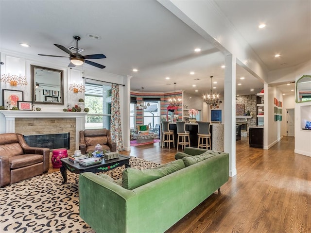 living room with hardwood / wood-style floors, ceiling fan with notable chandelier, and a fireplace