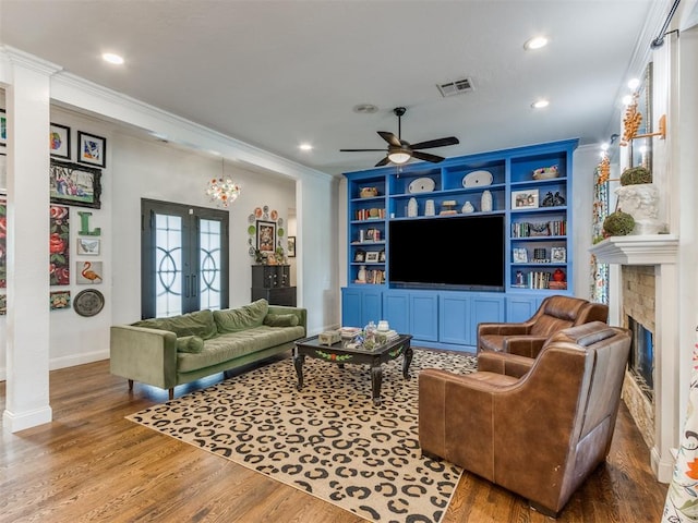 living room featuring built in features, wood-type flooring, ornamental molding, and french doors