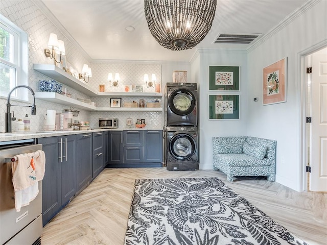 laundry area featuring stacked washer / drying machine, ornamental molding, sink, and light parquet flooring