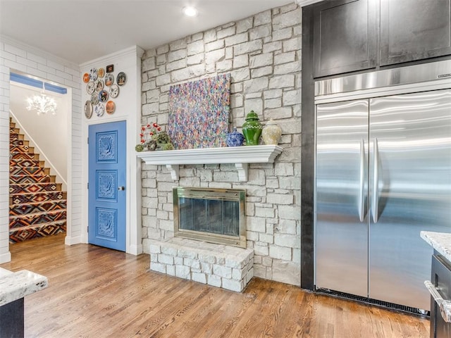 living room with light hardwood / wood-style floors, a stone fireplace, and ornamental molding