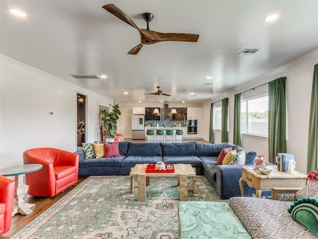 living room with hardwood / wood-style floors, ceiling fan, and crown molding