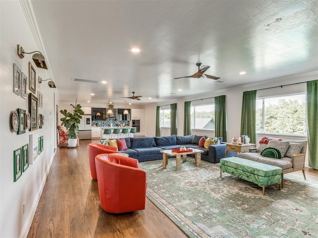 living room featuring hardwood / wood-style floors, ceiling fan, and ornamental molding