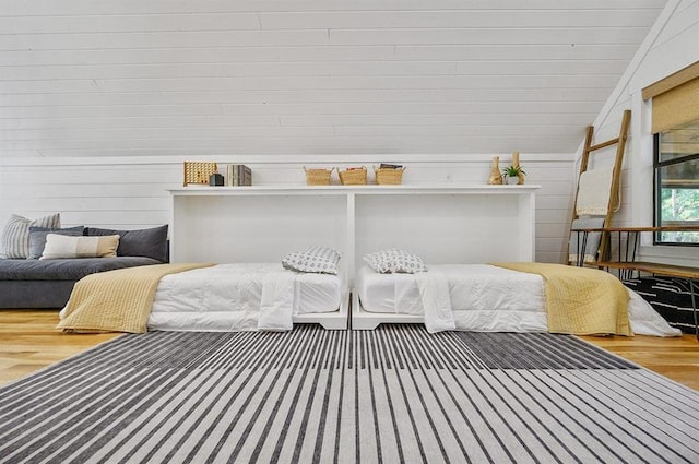 bedroom featuring hardwood / wood-style flooring, wood walls, and lofted ceiling