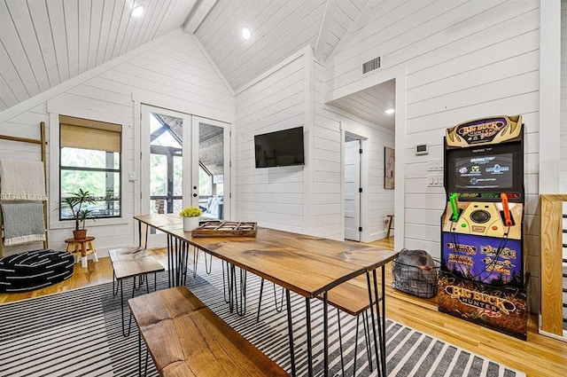 interior space with wood walls, light hardwood / wood-style floors, high vaulted ceiling, and french doors